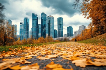 Poster - Autumnal park path leading to a modern cityscape under a cloudy sky.