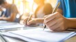 © atipong - Student taking exams writing examination on paper answer sheet optical form of standardized test on desk doing final exam in classroom Examination sitting on row chair in school