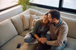 © Drazen - Affectionate couple embracing while relaxing on sofa.