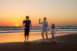 © Irina Schmidt - Three kids silhouettes running and jumping on beach at sunset. happy family, two school boys and one little preschool girl. Siblings having fun together. Bonding and family vacation.