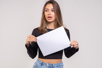 Beautiful young smiling brunette with a sheet of paper A4 close-up on a white background