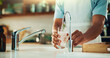 © peopleimages.com - Person, tap and hands with glass of water in kitchen for fresh drink, liquid and hydration. Sink closeup, thirsty or pouring pure beverage in container for nutrition, drinking or filtration in home