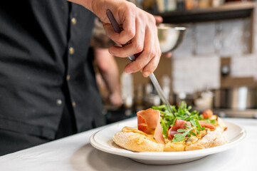 Wall Mural - A chef skillfully prepares a gourmet dish, featuring fresh salad and savory ingredients, highlighting culinary artistry in a restaurant kitchen setting.