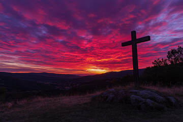 a wooden cross standing on a hill, illuminated by a radiant sunset or sunrise with vibrant hues of red, orange, and purple in the sky.