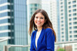 © Minerva Studio - Young businesswoman smiling in front of skyscrapers in modern city