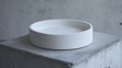 © cynz - A matte white dish on a raw concrete surface, exuding simplicity and clean lines