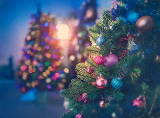 Poster - Close-up of a decorated Christmas tree at dusk.  Colorful ornaments adorn the branches, with blurred lights and other trees in the background creating a festive ambiance.
