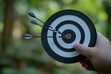 Poster - A hand grips a bullseye target with three sharp darts at the center, symbolizing success in personal and professional aspirations during the journey of selfimprovement and growth