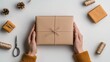 © Tuong - Christmas Crafts and Gifts: Top View of Hands Holding Envelope, Giftbox, and Decorative Items on White Background with Copyspace