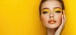 © Kien - Woman with yellow makeup and hand on head posing over bright background, copy space concept for beauty industry