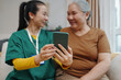 © DragonImages - Nurse showing apps in mobile phone to senior woman while they sitting in the room