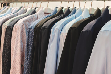 Poster - A row of shirts are hanging on a rack, with a blue shirt in the middle. The shirts are of various colors and styles, including a black shirt and a white shirt. The shirts are neatly folded