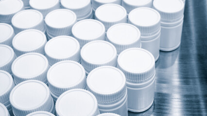 Poster - Row of white plastic containers with lids for medicines or vitamins or active dietary supplements on conveyor belt of pharmaceutical factory