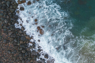 Poster - A rocky shoreline with a large body of water. The water is blue and the rocks are grey