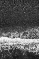 Poster - A black and white photo of the ocean with a wave. The water is choppy and the sky is dark