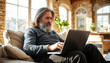 © Evgenii Starkov - A senior man with a cheerful expression works on a laptop in a bright and cozy room, showcasing the benefits of remote work and a relaxed lifestyle.
