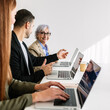 © Xavier Lorenzo - Vertical shot of businesspeople collaborating on laptops, engaging in teamwork and discussion during an office meeting. Business concept