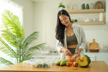 Wall Mural - Fitness young woman preparing meal containers with fresh vegetables in kitchen. Health and nutrition concept.