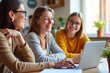 © SimpleDesignStudio - Three Happy Women Collaborating on Laptop in Bright, Modern Office Setting - Perfect for Teamwork and Productivity Concepts