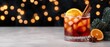 © Jeannaa - merry christmas spirit concept. A festive cocktail garnished with an orange slice and cinnamon sticks, set against a backdrop of warm, glimmering lights.