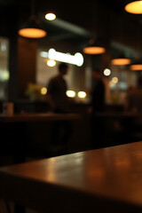 Poster - A blurred wood table is partially visible in the dimly lit background of a bustling nighttime café or restaurant scene._00005_