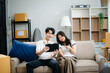 © laddawan - Young couple organizing belongings in a cozy home with boxes and luggage. Perfect for themes of moving