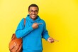 © luismolinero - African American student man over isolated yellow background surprised and pointing side