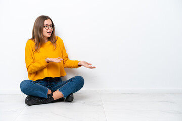 Wall Mural - Young caucasian woman sitting on the floor isolated on white background with surprise facial expression