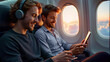 © Juan Mari - Two young men enjoy entertainment on their devices while sitting on a plane, with a sunset view outside the window. Ideal for promoting travel experiences, leisure activities, and in-flight services