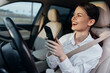 © SHOTPRIME STUDIO - Woman, car, cell phone, smiling a woman is seated in the driver's seat of a car, holding a cell phone and smiling at the camera, capturing a moment of cheerful communication and connectivity while on
