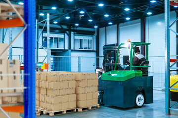 Poster - Warehouse inside. Pallets with boxes in storage. Forklift moves packages around warehouse. Distribution center interior. Storage area of an industrial enterprise. Warehouse interior with boxes