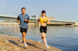 © muse studio - Two people jogging along a waterfront path on a sunny day in an urban environment