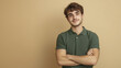 © Somporn Na Ubon - Cheerful young man with crossed arms, smiling against beige background. His casual green polo shirt adds to relaxed vibe of portrait, conveying confidence and approachability