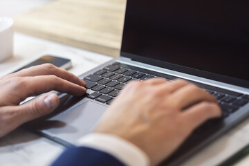 Poster - With the office setting blurred in the backdrop, the image shows a close-up of a man's hands typing on a contemporary laptop