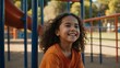 © Alteisen Riese - kid hispanic female in orange shirt on playground model portrait giggling for ad concept space for text