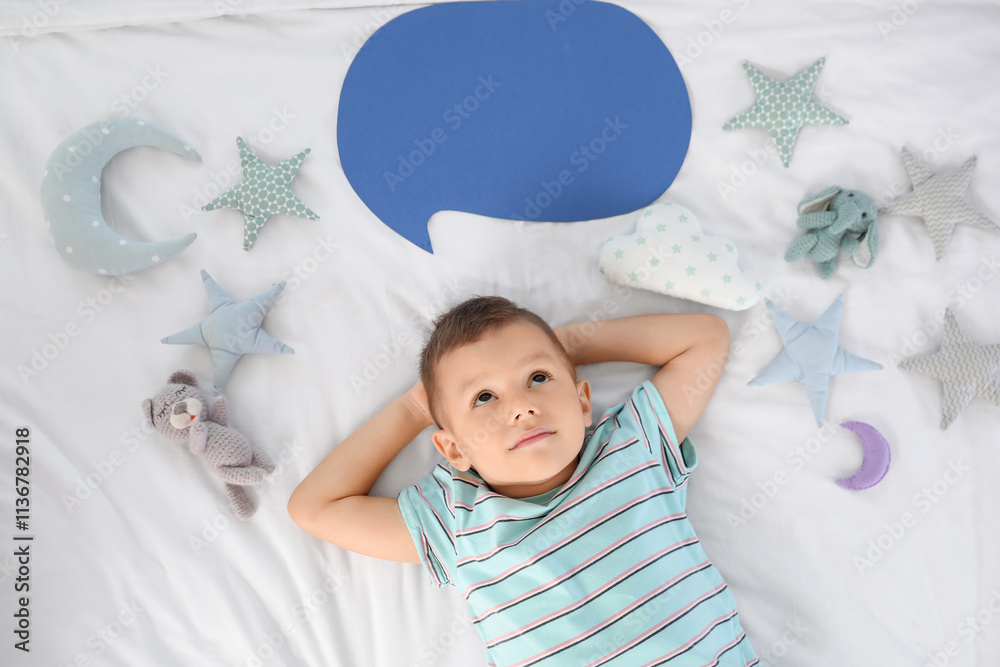 Dreaming little boy with blank speech bubble and toys on bed, top view