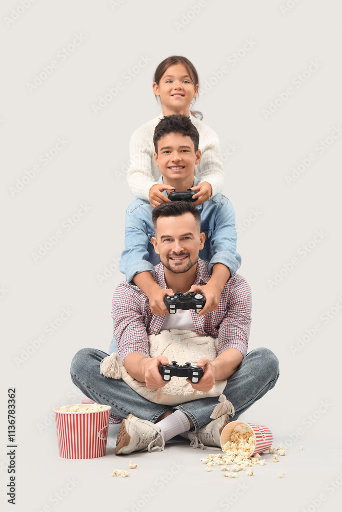 Father with his children playing video game on light background
