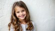 © Владлена Демидова - Smiling young girl with brown hair, children’s fashion ad against light wall.
