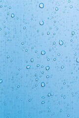 Poster - Close-up of raindrops on a blue background, creating a refreshing and tranquil atmosphere.