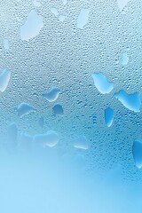 Poster - Close-up of water droplets on a blue glass surface, creating a serene and refreshing atmosphere.