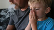 © vejaa - Father smoking near his child. Unhappy boy covers his nose from bad smell of smoke. Bad habits, smoking ban near children, harm of passive smoking. World No Tobacco Day, No Smoking Day background