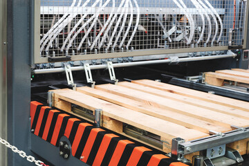 Poster - A palletizer is in operation with a chain hanging from it. The chain is connected to a metal bar