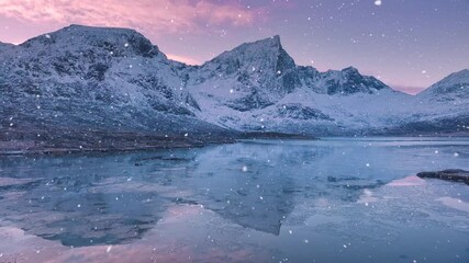 Wall Mural - aerial view from low flying drone of sea coast, fjord, snowy mountains in snowfall at sunset. winter