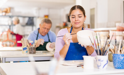 young woman has made craft bowl and is painting it