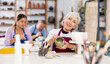 © JackF - woman at potter's master class finished painting vase that she had made earlier