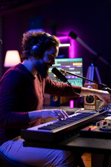 Aufkleber - Audio engineer playing piano electronic keyboard to compose a new song, singing on microphone and adjusting volume levels. Producer recording music, plays on midi controller gear.