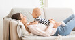 © Prostock-studio - Adorable newborn baby resting on sofa with mother, lying on her chest and smiling, panorama