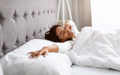 good start of sunny day. portrait of well-slept positive black lady stretching arms after waking up,