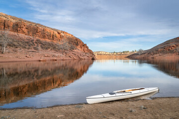 Wall Mural - decked expedition canoe with a wooden paddle on a rocky shore of Horsetooth Reservoir in northern Colorado in cold season scenery