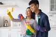 © Prostock-studio - Cute asian couple taking selfie while cleaning kitchen together, using sponge as smartphone, hugging and smiling, young man and woman having fun while house-keeping at home, side view